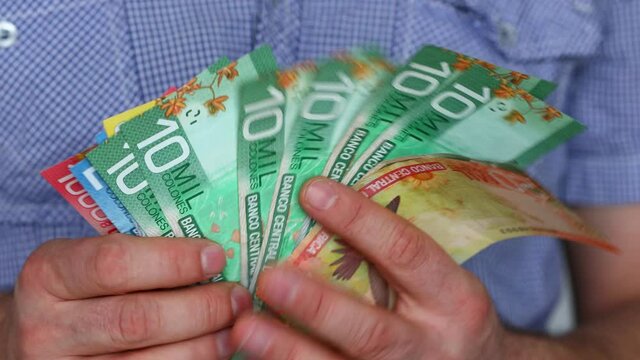 Costa Rican currency, Colones, Man in shirt watching and playing with large amounts of cash