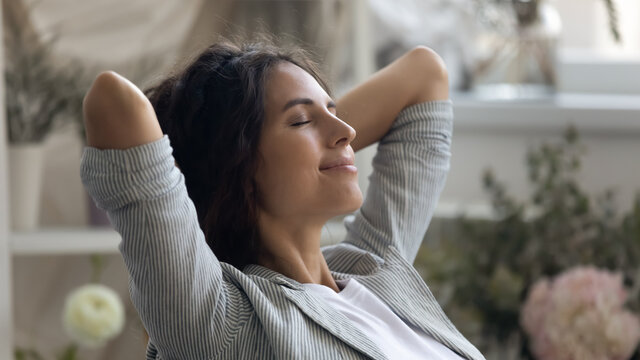 Close up of young Caucasian woman rest hands over head daydream or visualize relieve negative emotions. Happy calm millennial female relax with eyes close, meditate or sleep. Stress free concept.