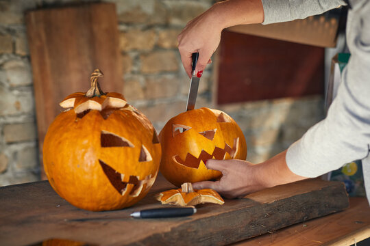 Woman carving Halloween pumpikn; Halloween pumpkin with a carved face
