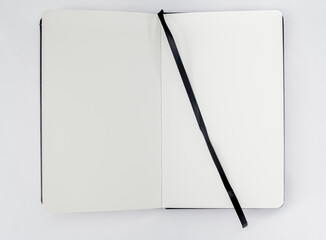 Unfold open notebook, book with blank white pages and black ribbon, bookmark on light background. Top view. Sketchbook.