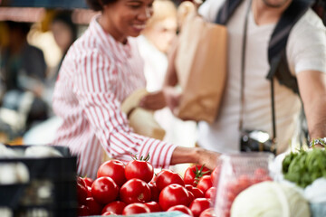 Sales of fresh and organic tomatos at the green market or farmers market.  Buyers choose and buy products for healthy food in grocery. All for diet healthy eating, lifestyle.