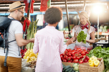 Seller woman offers fresh and organic vegetables at the green market or farmers market stall.  Young buyers choose and buy products for healthy food in grocery. All for diet healthy eating, lifestyle.