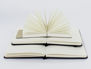 Three unfold notebooks lie on top of each other. Pyramid of books. Small fan open notepad with blank light beige pages. White background