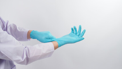 Doctor's hand is pulling blue latex gloves on white background.