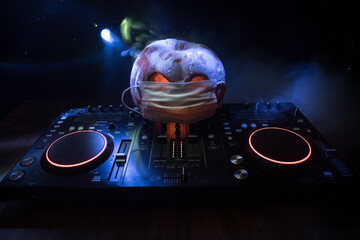 Halloween pumpkin on a dj table with headphones on dark background with copy space. Happy Halloween...