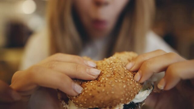 Teenager eating burger. Junk food, modern life concet. Filmed on cinema camera. 12 bit color space.