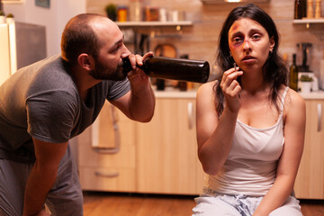 Drunk husband looking at bruised wife smoking. Woman in pain. Violent aggressive man abusing...