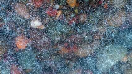 Fototapeta na wymiar texture of small stones covered with transparent river ice large snow crystals on ice 