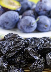 dried plum in the foreground plum on a white plate background blurred background top view red background vertical