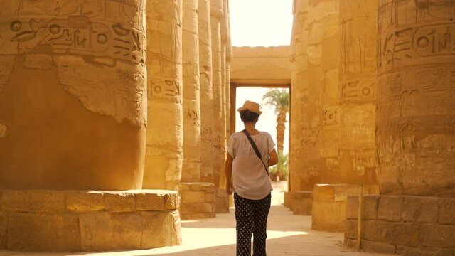 A young woman visiting the Karnak temple and its beautiful hieroglyphic columns, the great sanctuary of Amun. Egypt