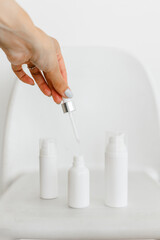 a woman's hand opens a white serum bottle on a white background