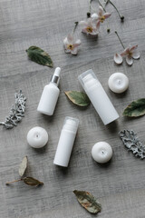 white bottles for cream and serum on a gray table with fresh flowers