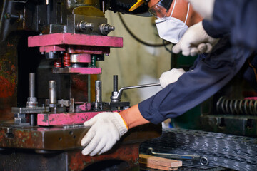 Worker maintains heavy industrial machine by metal wrench in manufacturer with supervisor order