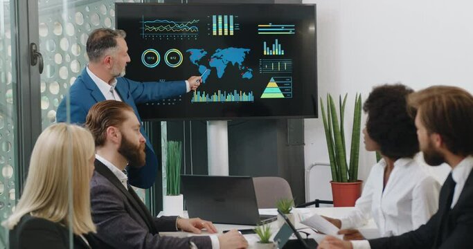 Good-looking confident attantive mixed race people listening their bearded chief which showing dynamics of ecological problems of planet using digital whiteboard