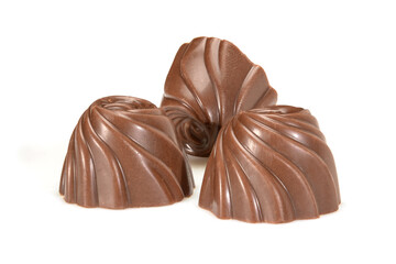 Chocolate pralines. Three dark chocolate bonbons with milk souffle fillings, macro close-up isolated on white background.