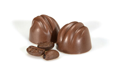 Chocolate pralines and coffee beans. Two dark chocolate bonbons with coffee souffle, macro close up isolated on white background.