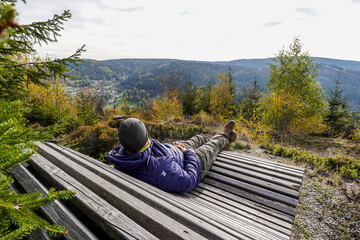 Ein Mann auf einer Holzliege mit schöner Aussicht in die Berge Warmensteinach Fichtelgebirge