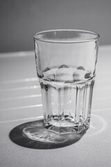 Empty heavy clear tumbler glass shot close up in strong light.