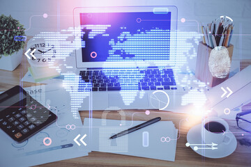 Double exposure of desktop with computer and world map hologram. International data network concept.