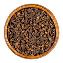 Cloves in a wooden bowl. Dried aromatic flower buds of the tree Syzygium aromaticum, used as spice, in cigarettes and to create a pomander. Close-up, from above, isolated over white, macro food photo.