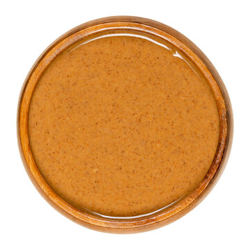 Smooth Almond Butter In A Wooden Bowl. Food Paste Made From Grinding Almonds Into A Nut Butter. Puree Of The Nuts Of Prunus Dulcis. Close-up From Above, Isolated On White Background, Macro Food Photo.