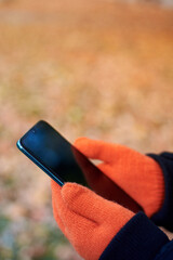 Woman's hands in orange gloves hold a smartphone.
