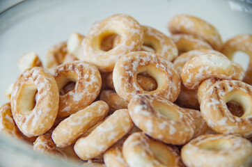 a bunch of sweet golden brown drying donuts with white powdered sugar lies in a white plate