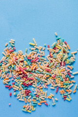 A handful of sugary colored noodles spilled on a blue table.