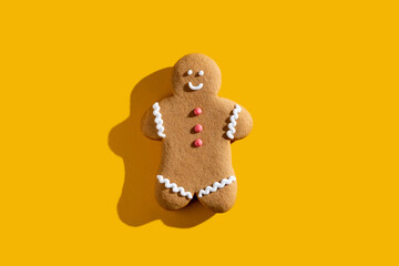 Xmas cookie. Festive bakery food. Winter holidays traditional ornament. Beige happy gingerbread man smiling isolated on yellow empty space background.