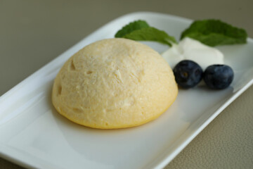 Cottage cheese casserole with blueberry berries and sour cream on white plate
