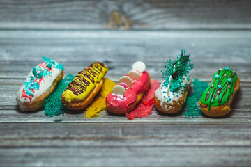 Amazing fresh colorful home-made eclairs close up. Delicious sweets. Tasty french multicolored eclairs with icing, cream, fresh berries decor elements. Original french multicolored eclairs.