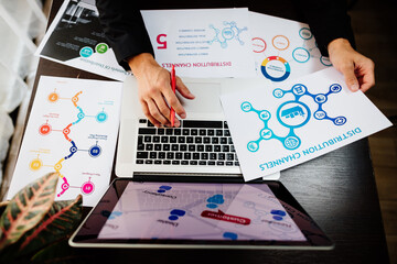 marketing manager making marketing distribution channels plan. Marketing manager desk with plans and strategy of distributive channels for new product. 