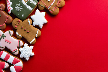 Red Xmas advertising background. Greeting card. Festive bakery food composition. Homemade gingerbread man cookie fun collection decorative arrangement for kids isolated on bright copy space.