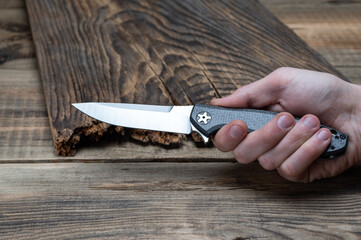 Knife with a white blade in hand. View of the knife in the hand from the side.