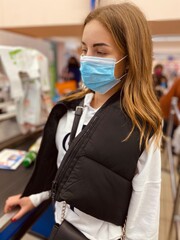young beautiful girl in medical mask against coronavirus at checkout in supermarket. Covid-19. Covid-20.