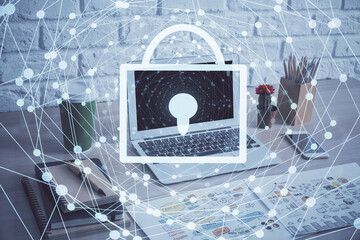 Double exposure of desktop with computer and lock icon hologram. Concept of data safety.