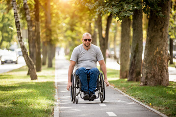 Handicapped man in wheelchair walk at the park alley