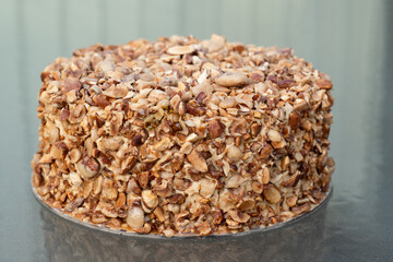 Beatiful nut biscuit cake finished with crushed sugar-coated candied caramelized almonds on a glass table