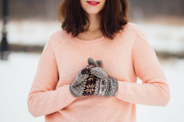 Young woman in winter in a pink sweater and mittens
