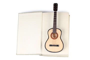Acoustic guitar model lies on an old book. Isolated objects on white background
