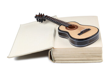 Acoustic guitar model lies on an old book. Isolated objects on white background