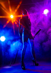 Beautiful slim sexy girl wearing lingerie and high heels posing holding katana sword in her hand in the rays of light in a colorful smoke. Artistic, conceptual, silhouette and advertising design