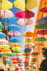 Fototapeta na wymiar Rue piétonne colorée de parapluie multicolore - Un arc en ciel de couleur à Carcassonne 