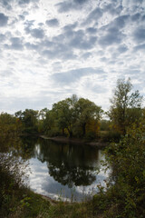 Autumn landscape, lake, shore, trees and cloudy sky