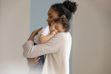 Loving young biracial mother hold in hands embrace small newborn baby child. Caring african...