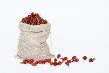 Linen bag with dried rose hips on a white background.