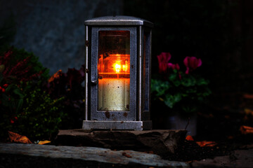 Grave lantern with burning candle at night in a cemetery