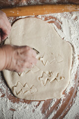 Creative Christmas cooking of homemade biscuits with woman's hands on a wooden  background, Flat lay.Grandma makes a cookie cutter
