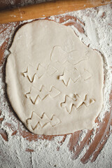 Creative Christmas cooking of homemade biscuits with woman's hands on a wooden  background, Flat lay.Grandma makes a cookie cutter

