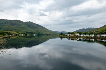 Fototapeta na wymiar Landscape with waters of Loch Duich with a town of Dornie, Scotland in Scottish overcast weather